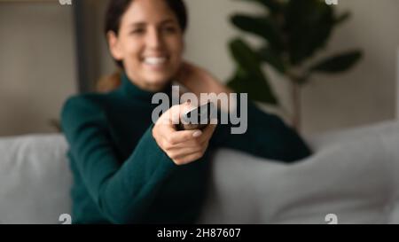 Glückliche Millennial weibliche Benutzer sitzen auf Sofa halten Fernbedienung Stockfoto