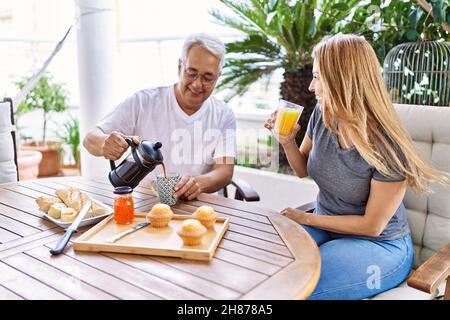 Das hispanische Paar mittleren Alters lächelte und freute sich beim Frühstück auf der Terrasse. Stockfoto