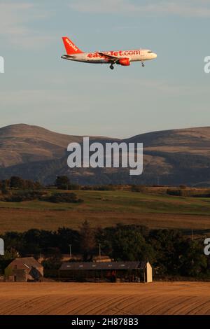 Mit den pentland Hills im Hintergrund macht sich ein easyjet-Flugzeug auf den Weg zum Flughafen Edinburgh, der von der Abendsonne beleuchtet wird Stockfoto