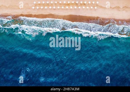 Banner Luftaufnahme des schönen Strandes mit weißen Sonnenschirmen und blauem Meer mit großen Wellen. Stockfoto