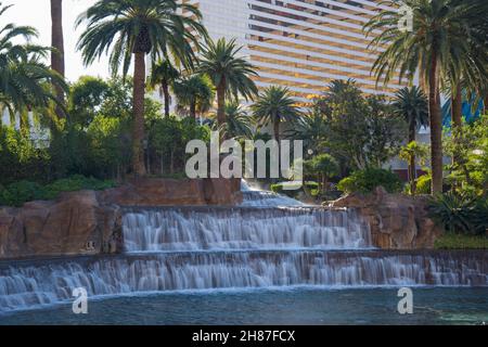 Las Vegas, Nevada, USA. Ein dekorativer Wasserfall, der in den Pool stürzt, inmitten üppiger tropischer Gärten vor dem Mirage Resort and Casino. Stockfoto