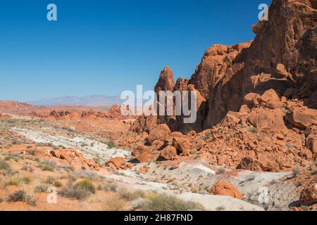 Valley of Fire State Park, Nevada, USA. Blick über die rote Wüstenlandschaft vom Fire Wave Trail unterhalb des Gibraltar Rock, den Mormon Mountains dahinter. Stockfoto