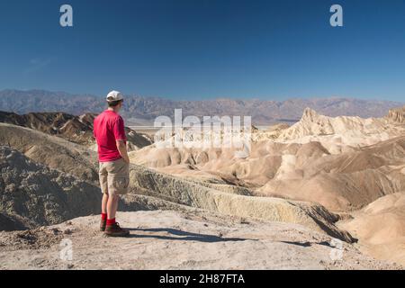 Death Valley National Park, Kalifornien, USA. Besucher bewundern den Blick vom Zabriskie Point über die karge Landschaft nach Manly Beacon und die Panamint Range. Stockfoto