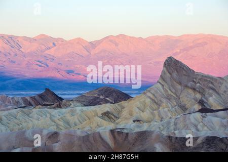 Death Valley National Park, Kalifornien, USA. Blick vom Zabriskie Point über die karge Wüstenlandschaft zum Manly Beacon und der Panamint Range, Sonnenaufgang. Stockfoto