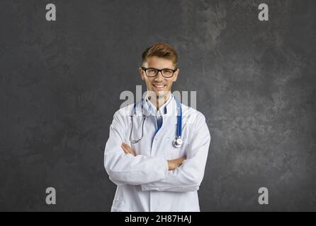 Studioportrait eines glücklichen männlichen Arztes, der mit gefalteten Armen steht und die Kamera anlächelt Stockfoto