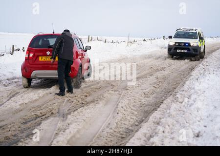 Fahrzeuge versuchen, auf der schneebedeckten A515 in der Nähe von Biggin im Peak District, Derbyshire, unter eisigen Bedingungen nach dem Sturm Arwen zu fahren. Bilddatum: Sonntag, 28. November 2021. Stockfoto