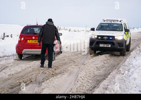 Fahrzeuge versuchen, auf der schneebedeckten A515 in der Nähe von Biggin im Peak District, Derbyshire, unter eisigen Bedingungen nach dem Sturm Arwen zu fahren. Bilddatum: Sonntag, 28. November 2021. Stockfoto