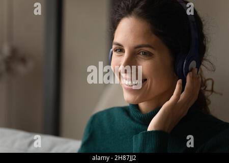 Junge Frau mit Ohrhörern, die online per Videocall mit dem Kunden spricht Stockfoto