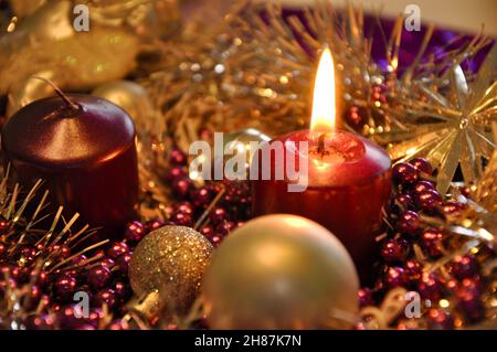 Adventkonzept Weihnachtslicht mit Kerzen Kugelkugel Sterne.Studioaufnahme eines schönen Adventkranzes mit Kugeln und brennender lilafarbener Kerze Stockfoto