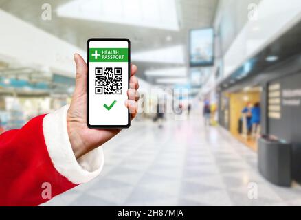 Der weihnachtsmann zeigt den Gesundheitspass der Impfung mit qr-Code auf dem Smartphone-Bildschirm Stockfoto