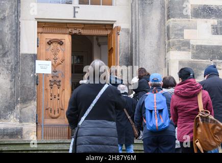 28. November 2021, Sachsen, Dresden: Menschen stehen vor der Frauenkirche, um sich bei einer Impfkampagne in der Unterkirche gegen das Coronavirus impfen zu lassen. Mit einer einzigartigen Impfkampagne in Kooperation mit dem Deutschen Roten Kreuz (DRK) zum ersten Advent wollen die sächsischen Kirchen Ärzte und mobile Teams dabei unterstützen, die Bevölkerung gegen Covid-19 zu impfen. Foto: Robert Michael/dpa-Zentralbild/dpa Stockfoto