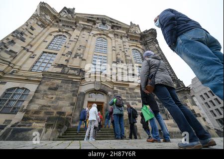 28. November 2021, Sachsen, Dresden: Menschen stehen vor der Frauenkirche, um sich bei einer Impfkampagne in der Unterkirche gegen das Coronavirus impfen zu lassen. Mit einer einzigartigen Impfkampagne in Kooperation mit dem Deutschen Roten Kreuz (DRK) zum ersten Advent wollen die sächsischen Kirchen Ärzte und mobile Teams dabei unterstützen, die Bevölkerung gegen Covid-19 zu impfen. Foto: Robert Michael/dpa-Zentralbild/dpa Stockfoto