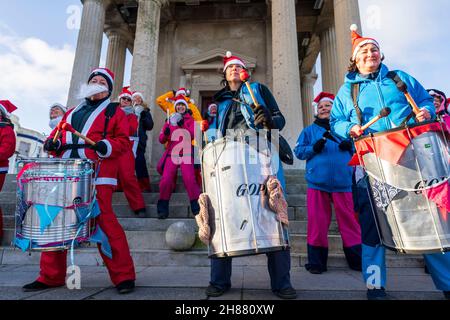 Blick aus der Perspektive auf die Percussion-Stahlband, die vor dem Uhrenturm an der Küste von Herne Bay auftrat, bevor an einem bitterkalten Morgen Ende November die Wohltätigkeitsveranstaltung „Santa's on the Bay“ an die Pilgerhospizen ging. Stockfoto