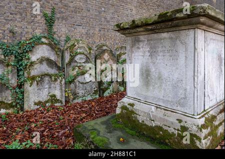 Uralt bewachsen mit Moos und Efeu Pflanzen Grabsteine und Gräber auf dem Kirchhof Garten am Herbstmorgen. Stockfoto