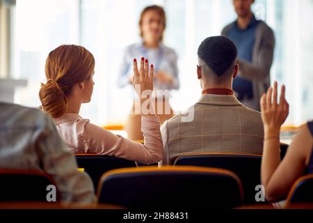 Junge Teilnehmer, die während eines Business-Vortrags in einer Arbeitsatmosphäre im Konferenzraum Fragen haben. Unternehmen, Leute, Meetings, Unternehmen Stockfoto