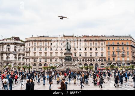 Die Menschen laufen entlang der Piazza Duomo vor dem Denkmal für Viktor Emmanuel II. Mailand, Italien Stockfoto