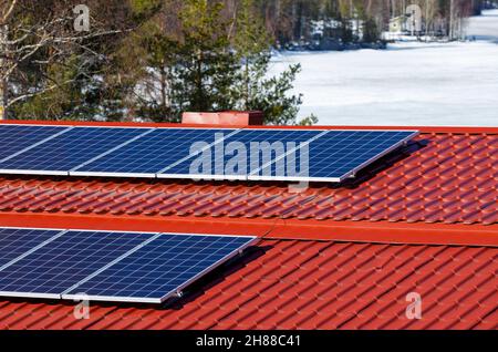 Sonnenkollektoren auf rotem Zinndach, Finnland Stockfoto