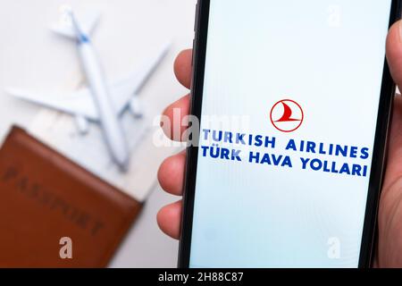 Ethiopian Airlines App auf dem Handy-Bildschirm in mans-Hand mit Flugzeug, Bordkarte und Reisepass im Hintergrund. Das Konzept der mobilen Anwendung der Fluggesellschaften. November 2021, San Francisco, USA Stockfoto