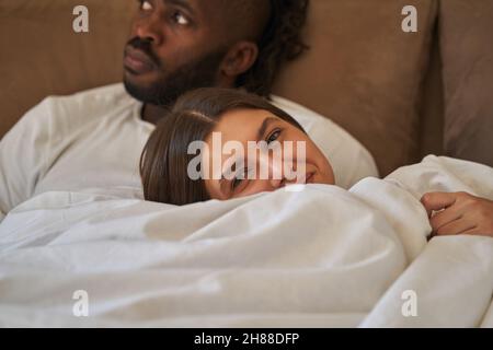 Zufrieden weibliche und nachdenkliche Männer liegen im Bett Stockfoto