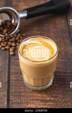 Cortado-Kaffee mit Kaffeebohnen daneben. Traditioneller Kaffee in Spanien. Stockfoto