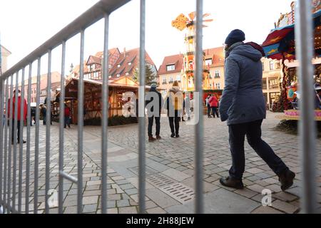 Quedlinburg, Deutschland. 28th. November 2021. Die Menschen besuchen den umzäunten Weihnachtsmarkt in der Adventstadt Quedlinburg. Der Weihnachtsmarkt ist einer von insgesamt zwei Märkten mit besonders hohen Corona-Anforderungen im Landkreis Harz, die eine Freilassungserlaubnis erhalten haben. Quelle: Matthias Bein/dpa-Zentralbild/dpa/Alamy Live News Stockfoto