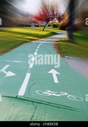 Grüner Radweg oder Radweg im Park mit herbstlich bunten Bäumen. Schnelle Bewegungsunschärfe. Stockfoto