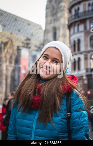 Porträt einer jungen Frau im Urlaub in Wien, Österreich. Glücklich lächelnde Frau mit langen Haaren auf der Stadtstraße. Stockfoto