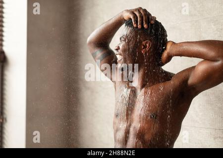 Afrikanischer Junger Mann Nimmt Dusche Waschkopf Im Modernen Badezimmer Stockfoto