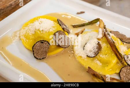 Italienische Küche, frisch hausgemachte rote Kartoffel gefüllte Pasta Tortellacci oder Ravioli Knödel mit Sommer schwarzen Trüffel und knusprigen grünen Spargel und geriebt Stockfoto