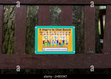 Woodbridge Suffolk UK July 07 2021: „Happy to Chat“-Zeichen auf einer Bank, die bei psychischer Gesundheit, sozialen Problemen und Einsamkeit helfen soll Stockfoto