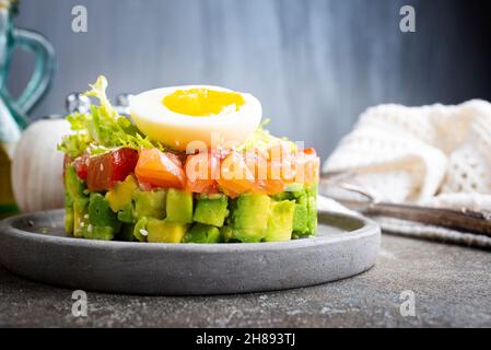 Lachstartare mit Avocado-Gurke, Zwiebeln, kleinen Blättern und gekochtem Ei Stockfoto