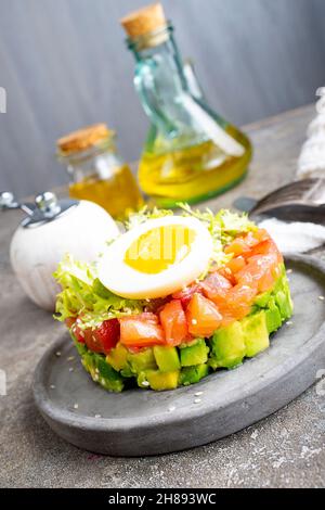 Lachstartare mit Avocado-Gurke, Zwiebeln, kleinen Blättern und gekochtem Ei Stockfoto