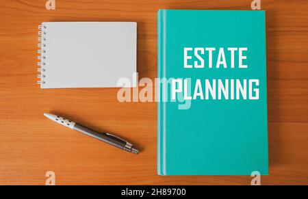 Text zur Immobilienplanung auf grünem Tagebuch, Schreibtisch mit Notizblock und Stift. Stockfoto