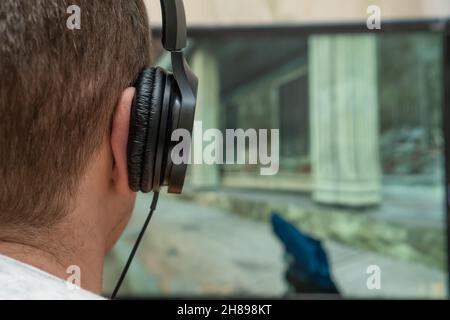 Nahaufnahme eines jungen Mannes mit Kopfhörern, der zu Hause ein Action-Videospiel auf einem Computer spielt Stockfoto