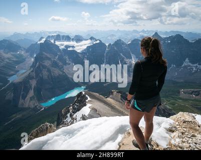 Weibliche Wanderin, die vom Gipfel des Mount Temple, Banff, Canadian Rockies, Kanada, auf den Moraine Lake blickt Stockfoto