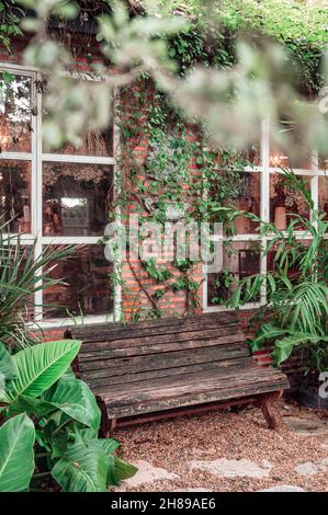 Holzbank von Backsteinhaus im tropischen Garten auf dem Hinterhof Stockfoto