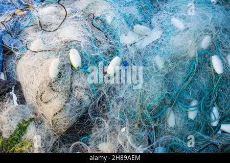 Blick hinunter auf blau-weiße, verworrene Seile und Fischernetze, gemischt mit Plastikschwimmern, aufgenommen am Worthing Beach West Sussex 25th. November 2021 Stockfoto