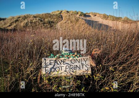 Auf einem Schild am Rhossili Strand auf der Gower Peninsula, auf dem die Leute aufgefordert werden, nur Fußabdrücke zu hinterlassen, neigen Urlauber dazu, Müll auf dem zu hinterlassen Stockfoto