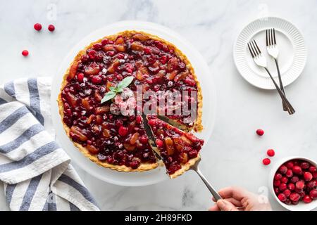 Draufsicht auf einen Cranberry-Tart, wobei eine Scheibe entfernt wird. Stockfoto