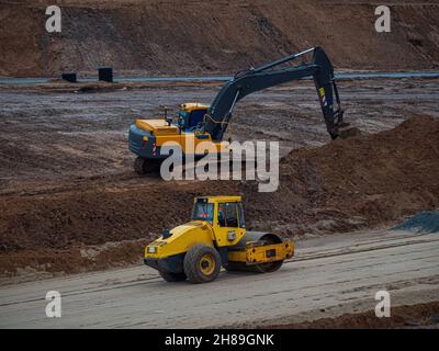 Straßenwalze und Bagger auf dem Bau einer neuen Straße. Details zur Autobahn-Baustelle Stockfoto