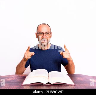 Glücklicher reifer Mann, der die Lösung für das fand, was er suchte, in einem Buch, das mit seinem Finger zeigte, isoliert auf dem Hintergrund. Stockfoto