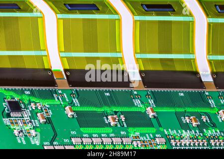 Elektronische Bauteile auf der Leiterplatte mit gedruckten mehradrigen Verbindungen in der Baugruppe mit gebogenem, flexiblem Teil. Kunststoff-FPC-Schnittstelle für ein LCD-Gerät. Stockfoto