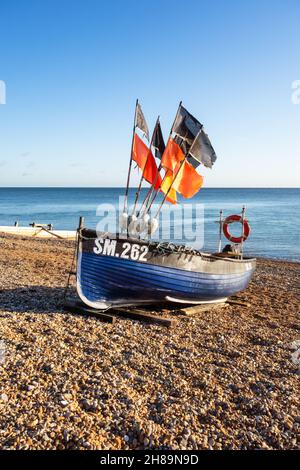 SM.262 Traditionelles blaues Fischerboot, das an einem Kiesstrand mit farbenfrohen Flaggen festgemacht wurde, aufgenommen in Worthing West Sussex 25th vom November 2021 Stockfoto