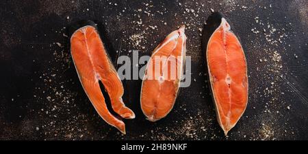 Steaks aus Chum Lachs roh mit Gewürzen, Kräutern, Salz und Zitrone auf altem Steingrund. Kopiespeicherplatz in der Draufsicht. Stockfoto