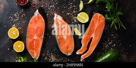 Steaks aus Chum Lachs roh mit Gewürzen, Kräutern, Salz und Zitrone auf altem Steingrund. Kopiespeicherplatz in der Draufsicht. Stockfoto