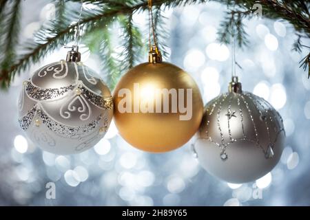 Weihnachtsschmuck. Dekorierter Zweig des weihnachtsbaums mit drei Kugeln auf Bokeh Hintergrund Stockfoto