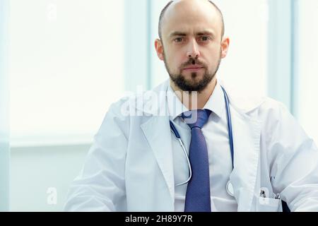 Nahaufnahme. Ernsthafter Arzt sitzt an seinem Schreibtisch. Stockfoto