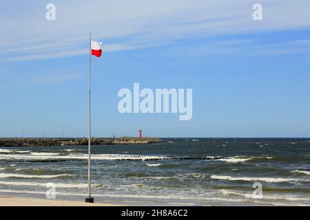 Die Flagge Polens befindet sich auf einem Mast am Strand, an der Ostseeküste in Kolobrzeg, Polen. Stockfoto