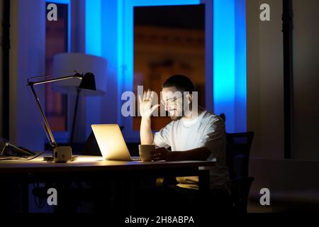 Junger Geschäftsmann, Student oder Dozent schauen in Laptop-Webkamera winkende Hand aufnehmen Online-Webinar Stockfoto
