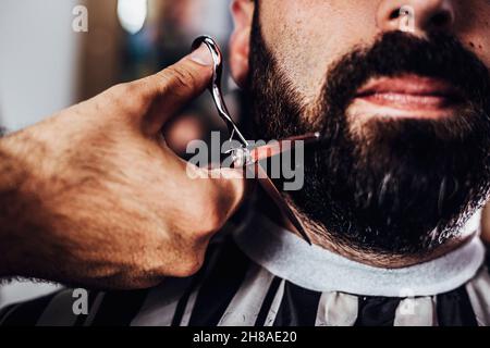 Barber schneidet einem Kunden den Bart mit einer Schere. Bartschnitt im Friseurladen. Stockfoto
